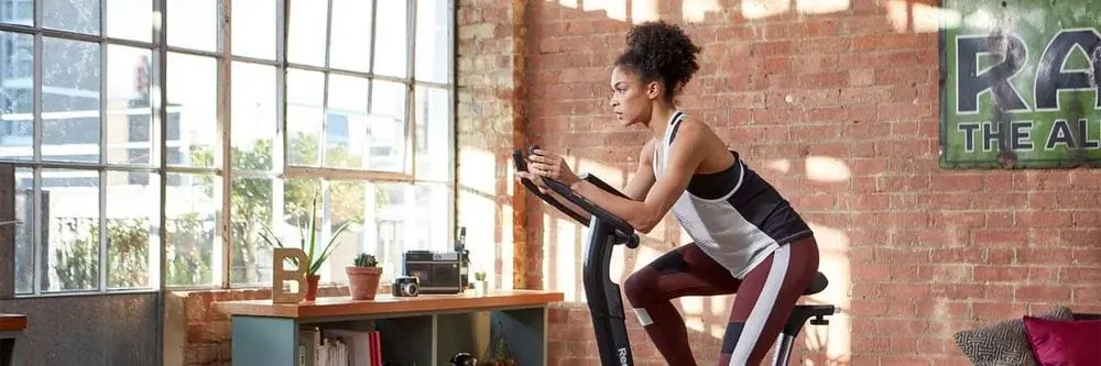 Athletic Girl On Fitness Spin Bike At Home